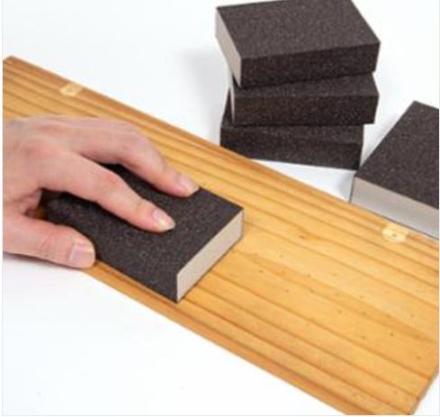 Woodworker using a sanding block on a wooden board surface