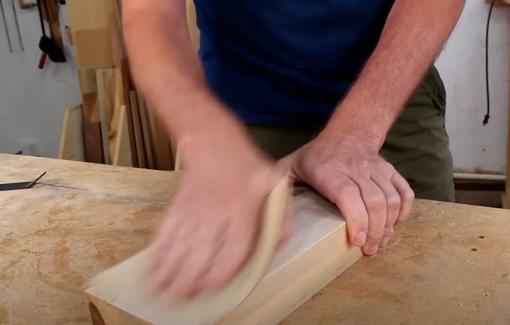 Woodworker using an electric power sander on a tabletop project